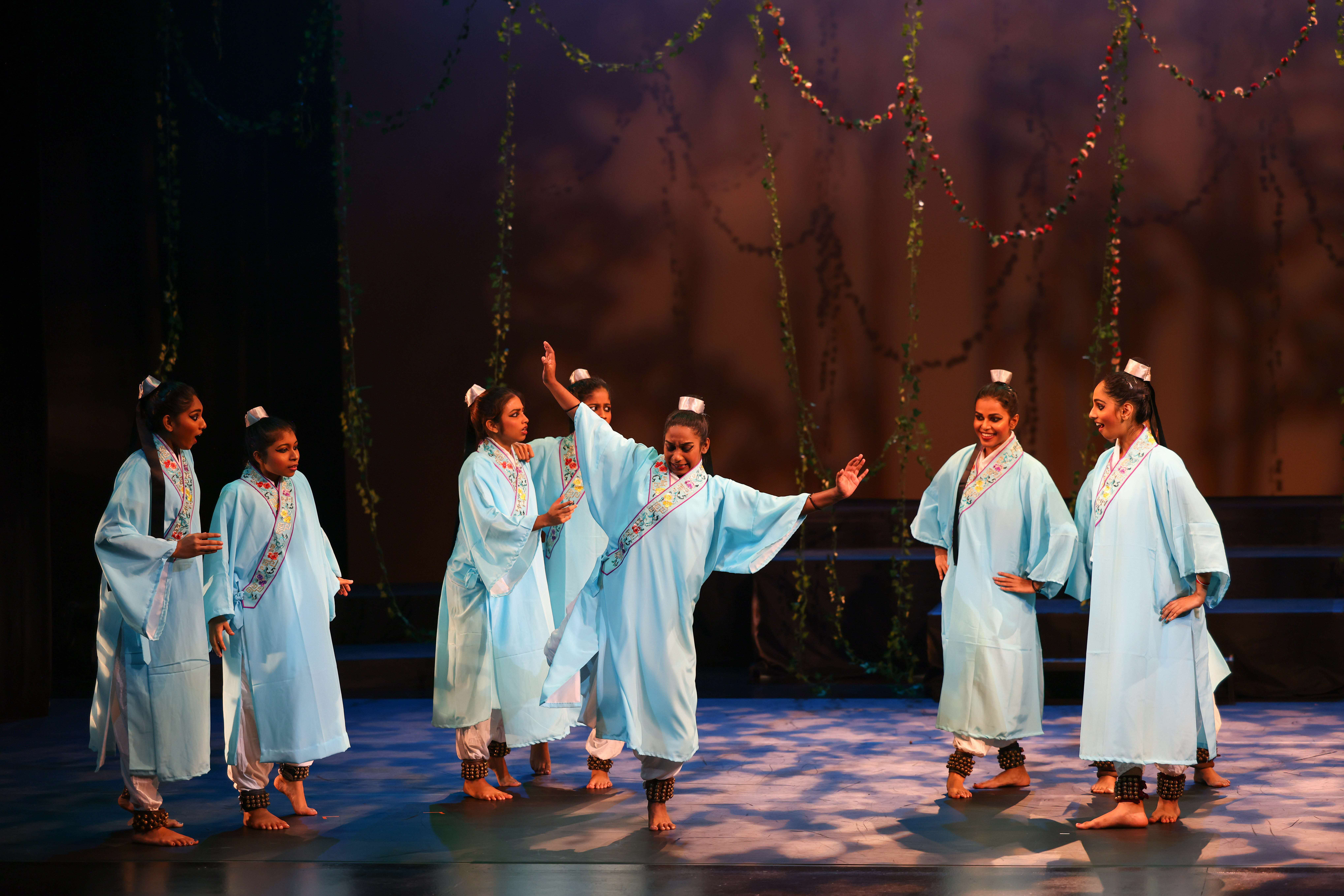 A group of performers in light blue traditional Chinese robes performing on stage.  "Butterfly Lovers": A Timeless Tale Reimagined Through Generations