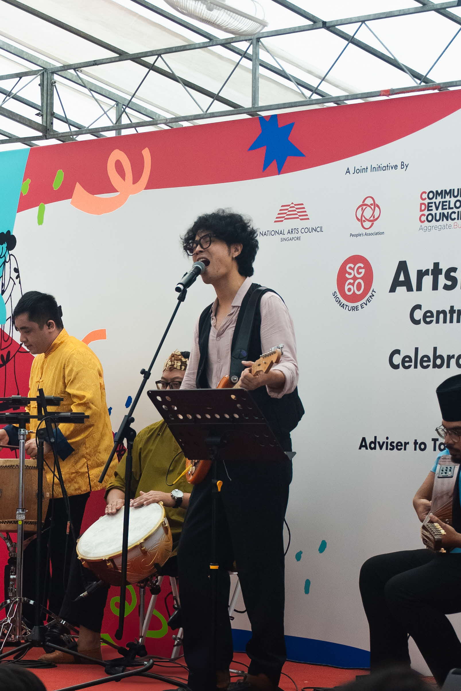 Tony Guo (centre) from yIN Harmony playing the guitar at an ArtsEverywhere@CDC performance. A guitarist from yIN Harmony smiling and performing on stage. Discover Joy Together: ArtsEverywhere@CDC — Creating Family Memories through Art