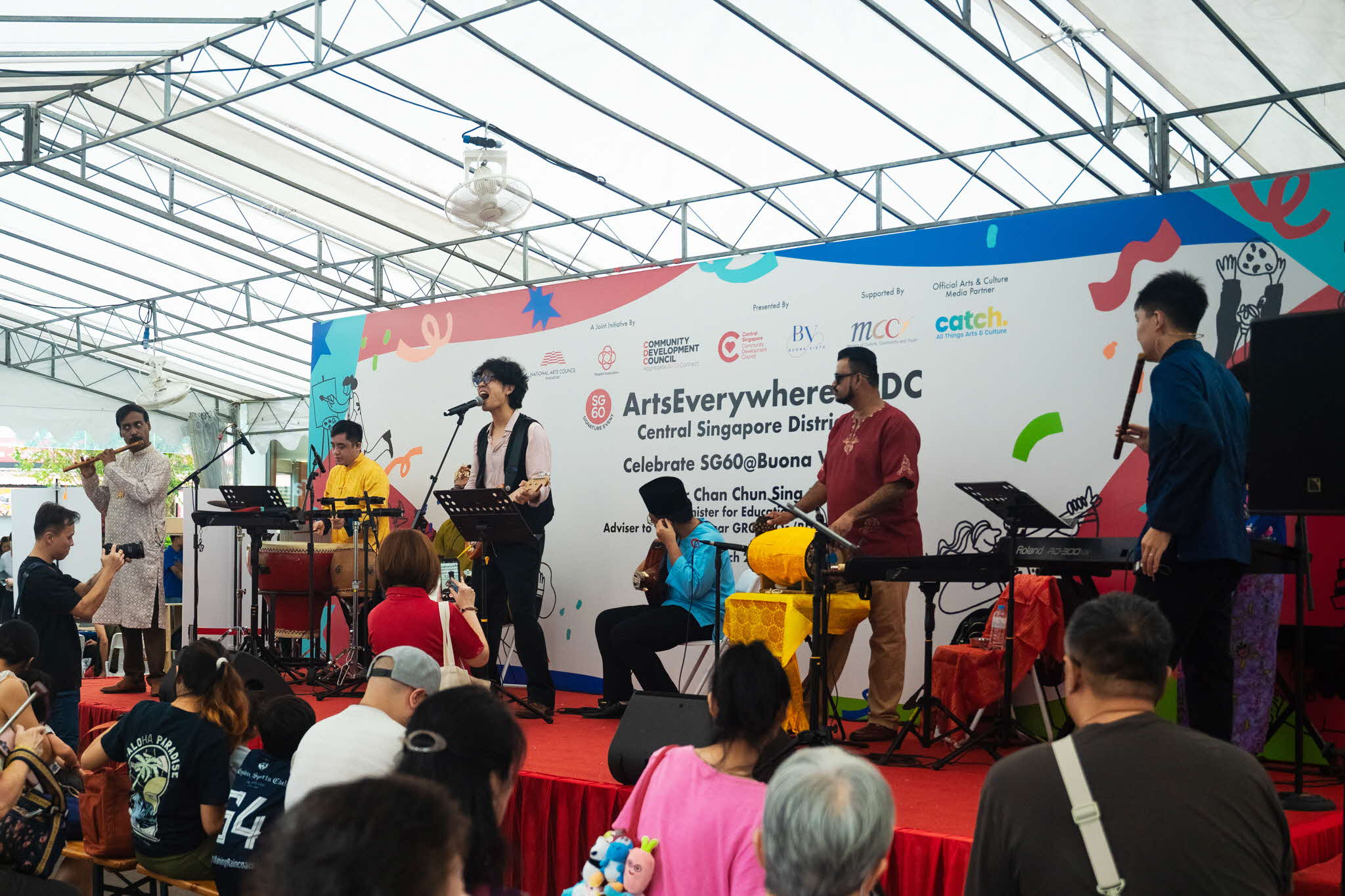 Multi-ethnic music group yIN Harmony performing at ArtsEverywhere@CDC Seven performers singing and playing instruments on stage before a crowd at ArtsEverywhere@CDC. Discover Joy Together: ArtsEverywhere@CDC — Creating Family Memories through Art
