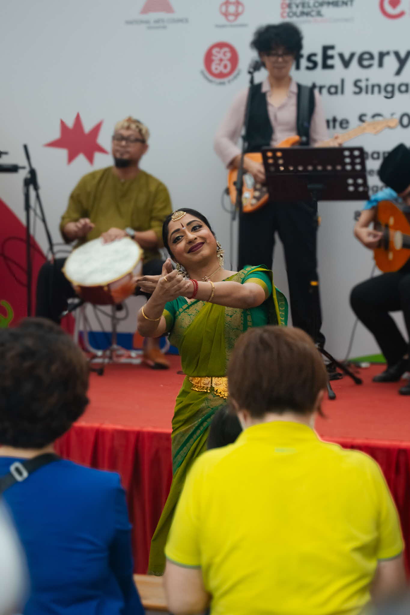 Multi-ethnic music group yIN Harmony performing at ArtsEverywhere@CDC A dancer in a green saree doing a traditional dance move as a band plays instruments behind her on stage at ArtsEverywhere@CDC. Discover Joy Together: ArtsEverywhere@CDC — Creating Family Memories through Art
