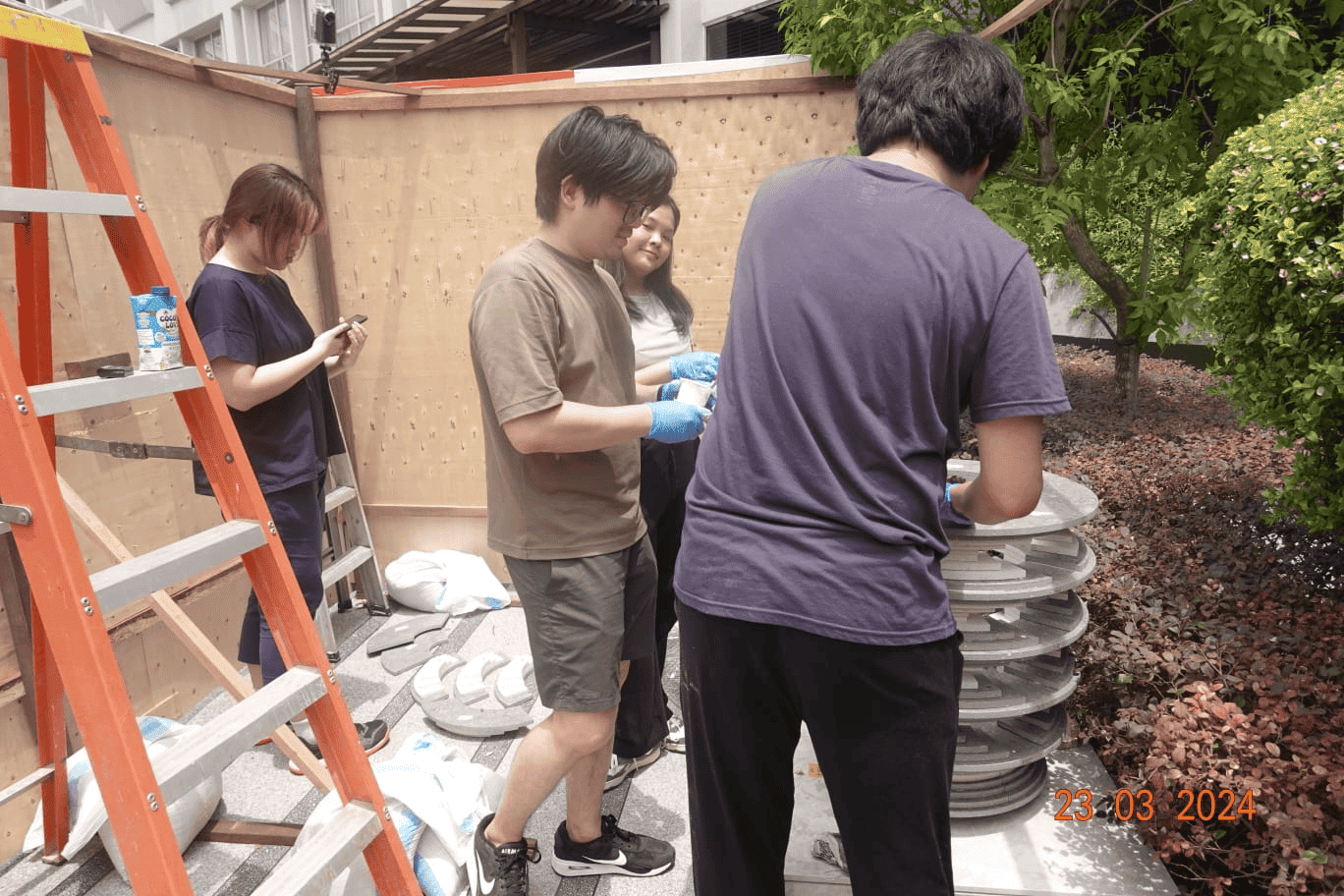 A behind-the scenes look at ‘Strata’ and its development A behind-the-scenes photograph of people examining and working on the stacked disc sculpture, which is only completed till waist-level